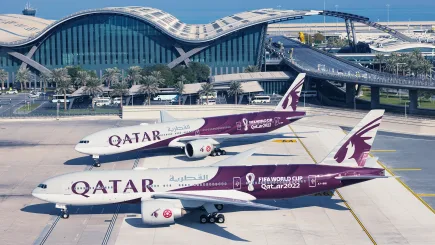 Aerial view of Qatar Airways aircraft on the tarmac at Hamad International Airport in Doha, with the iconic wave-form terminal building in the background, representing the high-security aviation environments where TrustForce Security provides professional airport security services in Qatar.