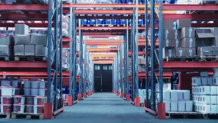 Large industrial warehouse with tall shelving racks stocked with goods and materials, representing the type of commercial storage facility where TrustForce Security provides professional manned guarding and warehouse security services across Qatar.
