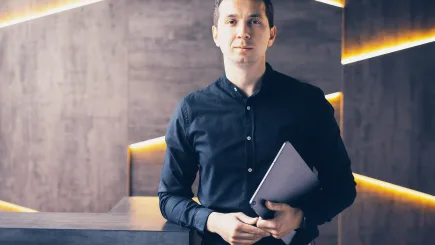 Smartly dressed professional holding a tablet in a modern office environment, representing the personal assistant support element of TrustForce Security's executive protection services for VIPs and business leaders in Qatar.