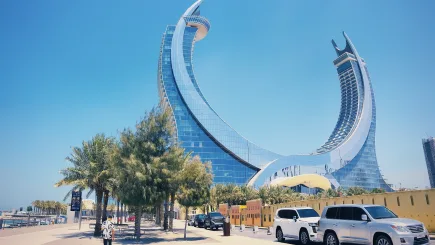 Exterior view of the iconic Katara Towers hotel in Lusail, Qatar, with luxury vehicles and palm-lined promenade in the foreground, representing the premium hospitality environments where TrustForce Security provides professional hotel security services across Qatar.