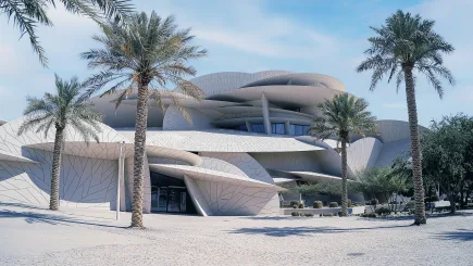 Exterior view of the National Museum of Qatar in Doha, with its distinctive interlocking disc architecture surrounded by palm trees, representing the prestigious cultural institutions where TrustForce Security provides specialist museum security services in Qatar.