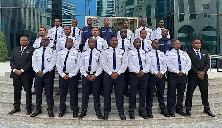 Group photo of TrustForce security guards in Doha, Qatar, dressed in white and navy uniforms, standing in formation on building steps.