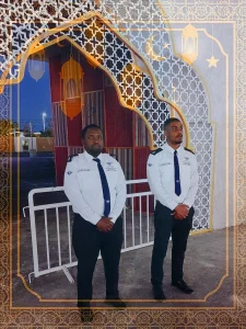 Two uniformed TrustForce security guards standing post at a Ramadan village entrance in Doha, Qatar